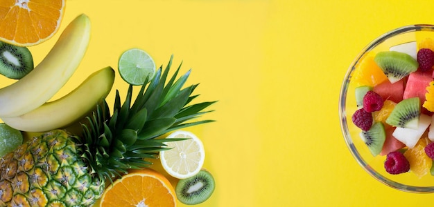 Banner Tropische Früchte und Obstsalat in der Glasschale auf gelbem Hintergrund Nahaufnahme Kopierbereich