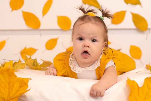 Banner Uma criança feliz em um terno laranja brilhante deitado de bruços em um fundo de outono um bebê sorridente uma criança de seis meses Um recém-nascido saudável Humor de outono Conceito de produtos infantis
