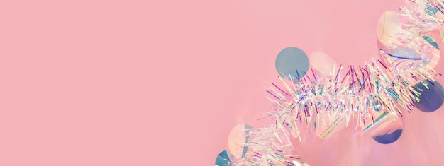 Banner web navideño con guirnalda de oropel sobre fondo rosa.