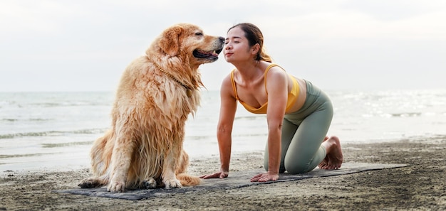 Bannergröße Foto eine asiatische junge Frau küsst ihren Hund auf einer Yogamatte am Strand Entspannung mit a