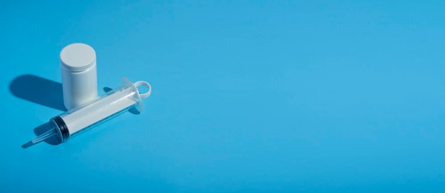 Foto bannerpills seringa para um cateter em um fundo médico azul close-up vista de cima tubo de seringa médica com vitaminas