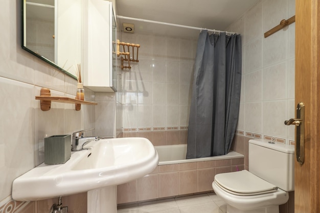 Baño del apartamento con bañera con cortina de ducha gris.