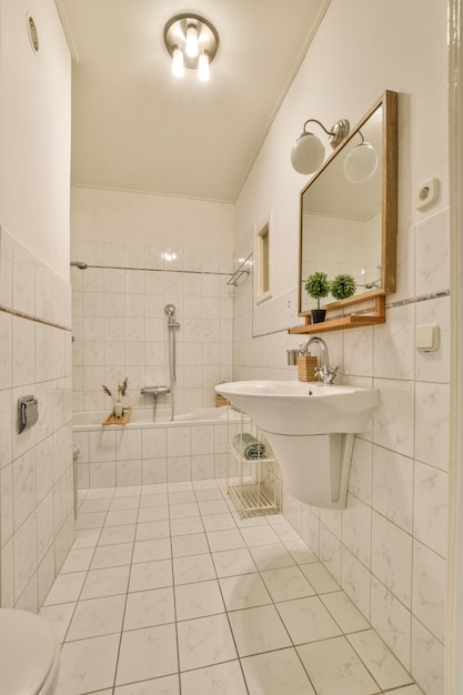 Un baño con azulejos blancos y molduras de madera alrededor de la tina, lavabo y espejo en la pared