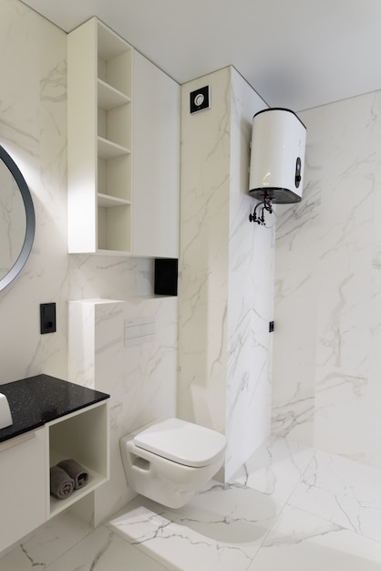 Baño moderno y espacioso con baldosas de mármol con bañera y lavabo de inodoro blancos y frescos Vista lateral