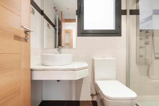 Baño con sobre de mármol blanco y lavabo de porcelana con plato de ducha y espejo rectangular sin marco