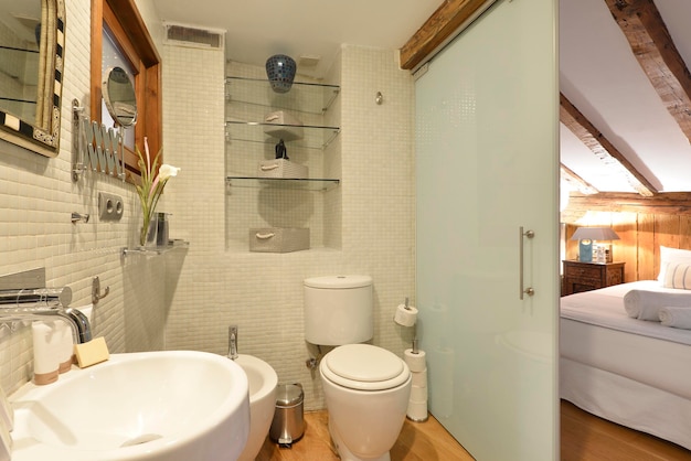 Baño en suite con puerta corrediza de vidrio translúcido de azulejos y sanitarios de diseño en porcelana blanca