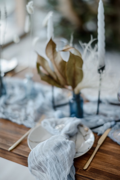 Banquete de boda. Decoración festiva en colores vivos. Mesa de madera con cubiertos, velas, flores secas y lino azul cielo.