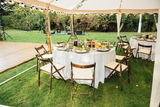 Banquete de bodas Las sillas y la mesa redonda para invitados se sirven con cubiertos, flores verdes y vajilla y se cubren con un mantel blanco color oliva