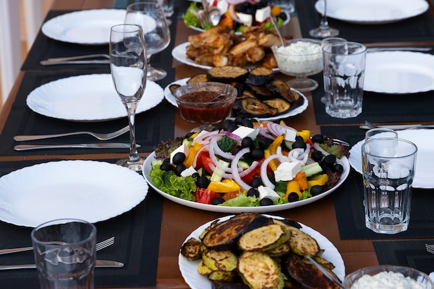 Foto banquete servido, mesa de comedor con platos, botanas, copas de vino y agua, cocina europea. enfoque selectivo.