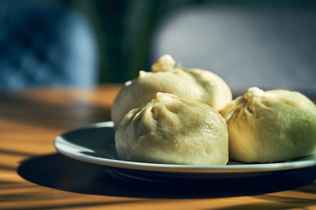 Baozi con diferentes rellenos (ternera o cerdo) en un plato blanco. Receta y cocina china. Bollo de carne al vapor chino