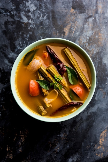 Foto baqueta de curry ou shevga sheng bhaji ou sambar do sul da índia, servido em uma tigela sobre um fundo temperamental. foco seletivo