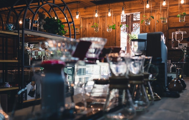 Un bar con una barra con cafetera y vasos en el mostrador.