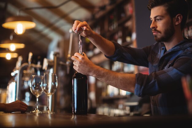 Bar tender masculino abrindo garrafa de vinho