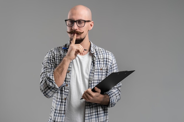 Barba careca bonita pensativa com homem de bigode vestindo roupas casuais segurando a prancheta isolada