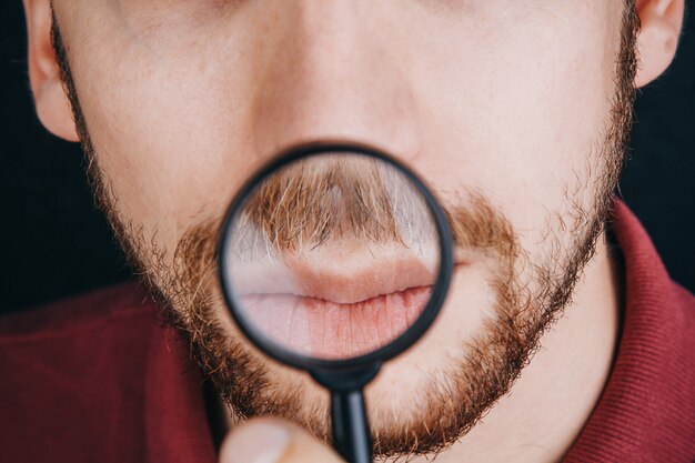 Barba sob uma lupa. linha fina no fim da cara de um homem acima.