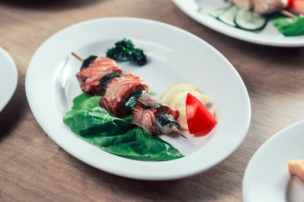 Barbacoa en brochetas de madera con verduras frescas.