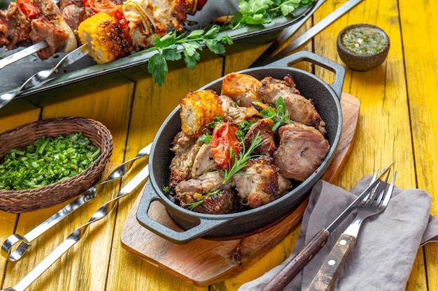 Barbacoa de carne a la parrilla cerdo pollo y verduras en sartén de hierro fundido Brochetas a la parrilla sobre fondo de madera amarilla Vista superior