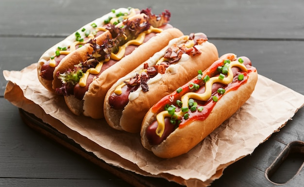 Foto barbacoa hot dogs a la parrilla con mostaza americana amarilla, sobre un fondo de madera oscura