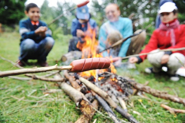 Barbacoa en la naturaleza, grupo de personas que preparan las salchichas en el fuego (nota: dof bajo)