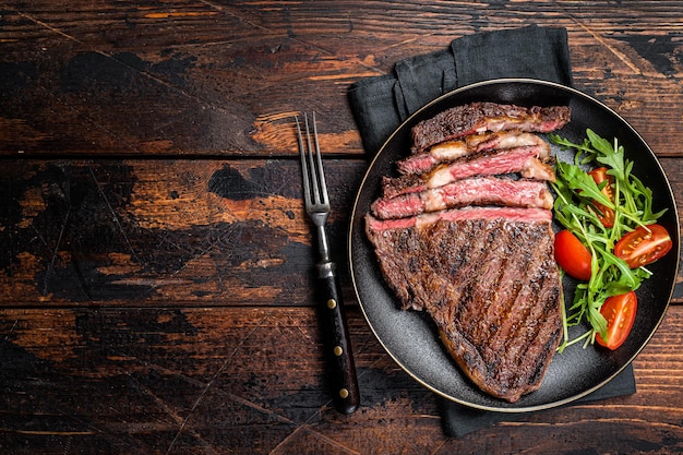 Barbacoa a la parrilla y en rodajas wagyu Rib Eye filete de carne de res en un plato Fondo oscuro Vista superior Espacio de copia