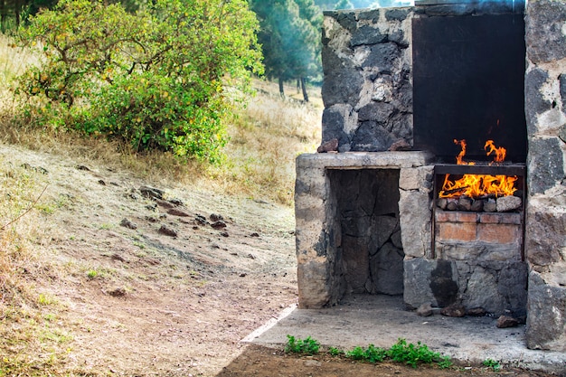 Barbacoa de piedra, con fuego, al aire libre.