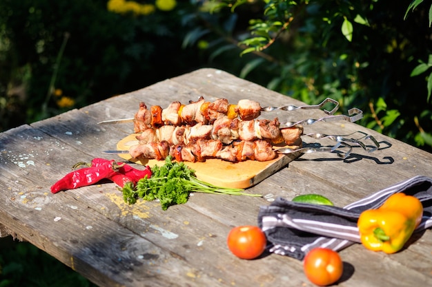 Barbacoa y verduras recién cocidas en una mesa de madera. Almuerzo de verano en la naturaleza.