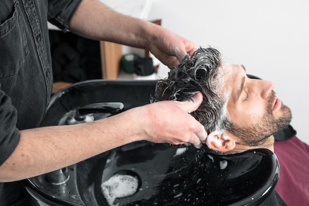 Barbearia Cabeleireiro lava a cabeça do cliente na barbearia Fotografia de alta qualidade