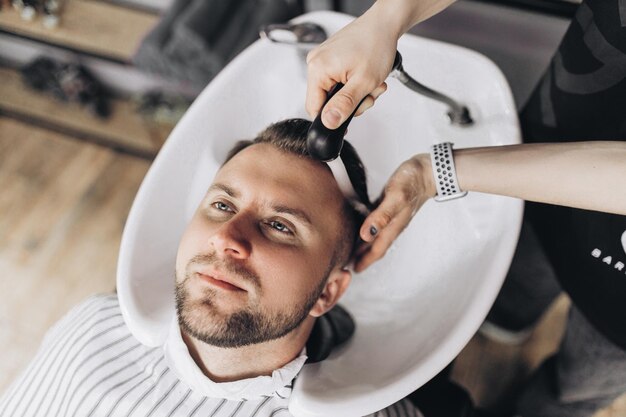 Barbearia cabeleireiro lava a cabeça do cliente na barbearia fotografia de alta qualidade