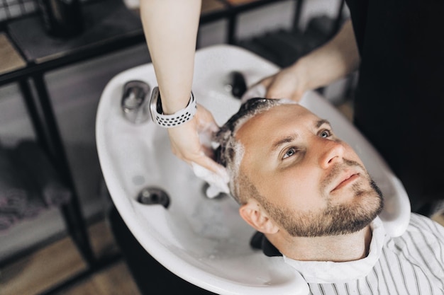 Barbearia Cabeleireiro lava a cabeça do cliente na barbearia Fotografia de alta qualidade