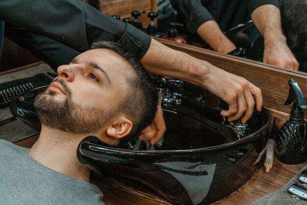 Barbearia, um homem é lavado o cabelo. barber lava seu cliente. lave os cabelos e as barbas após o corte. cuidado pessoal