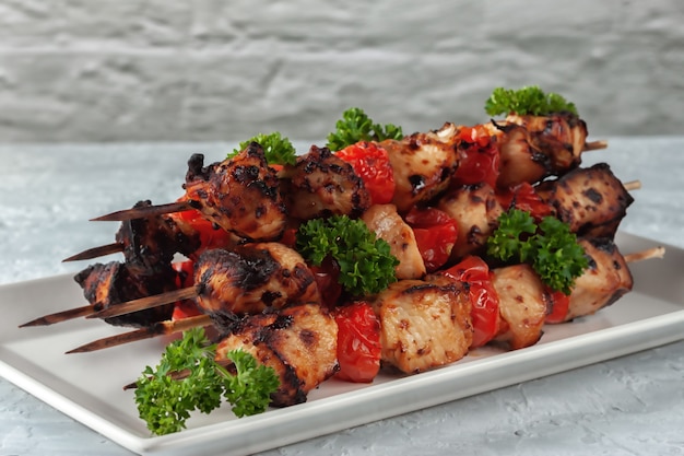 Barbecue des Huhns am Spieß mit Gemüse auf grauem Hintergrund