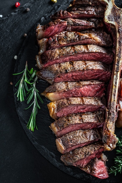 Barbecue Dry Agyu Porterhouse Rindersteak in Scheiben geschnitten mit großem Filetstück. Hintergrund für Lebensmittelrezepte. Nahaufnahme. vertikales Bild.