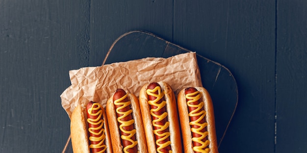 Barbecue gegrillte Hot Dogs mit gelbem amerikanischem Senf, auf dunklem Holzhintergrund