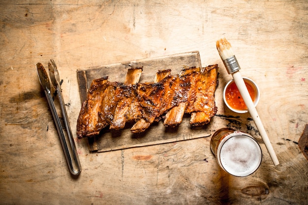 Barbecue-Schweinerippchen mit Tomatensauce und Bier auf hölzernem Hintergrund