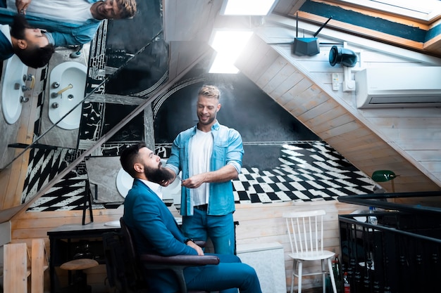 Barbeiro aparando barba para seu cliente