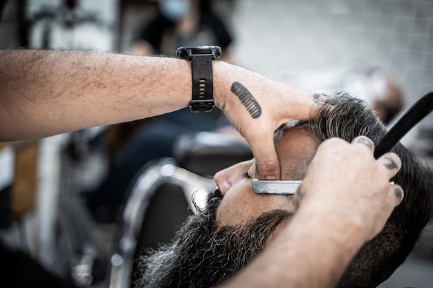 Barbeiro barbeando um cliente em uma barbearia