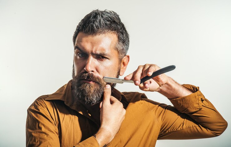 Foto barbeiro com barbeadora reta homem em barbearia barbeando barbeiro barba barbeadora retrato homem barbudo com barbeador vintage homem bigode cliente barbudo visita barbearia