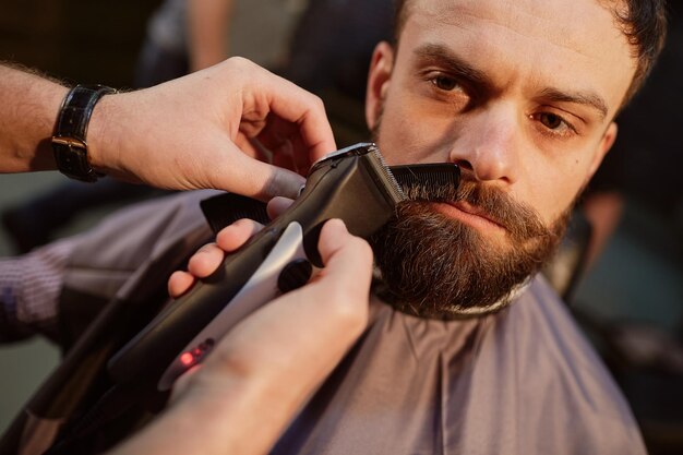 Barbeiro corta a barba no serviço de barbeiro de barbearia