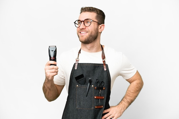 Barbeiro de avental sobre fundo branco isolado, posando com os braços no quadril e sorrindo