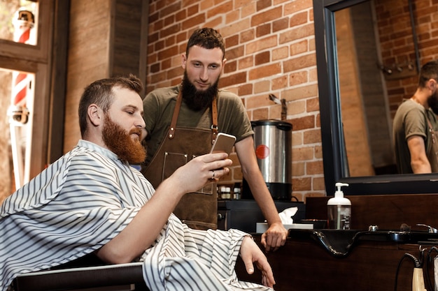 Foto barbeiro e homem barbudo na barbearia