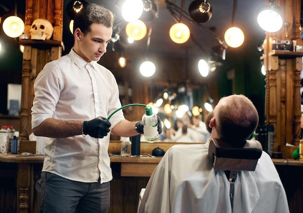 Barbeiro finalizando corte de cabelo e barbear Fase final de atendimento ao cliente em salão de cabeleireiro profissional para homens