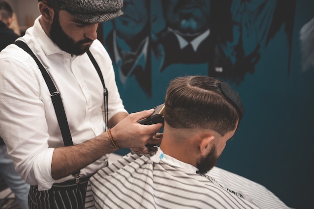 Barbeiro homem depila cliente na barbearia.