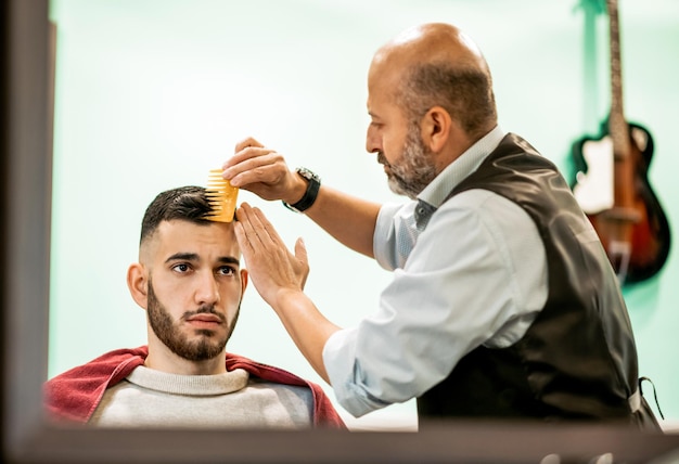 Barbeiro penteando o cabelo dos clientes na barbearia