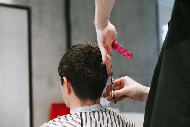 Barbeiro profissional corta o cabelo do cliente com tesoura em uma barbearia foto próxima