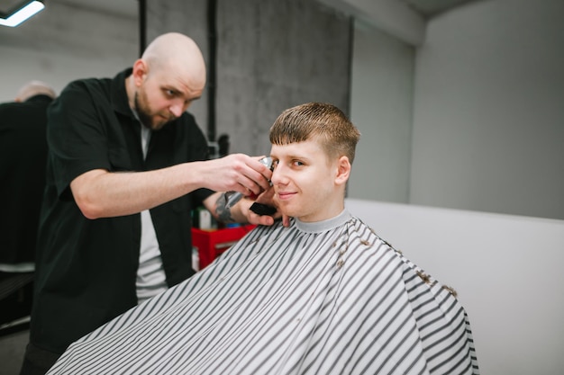 Barbeiro profissional corta um jovem cliente positivo