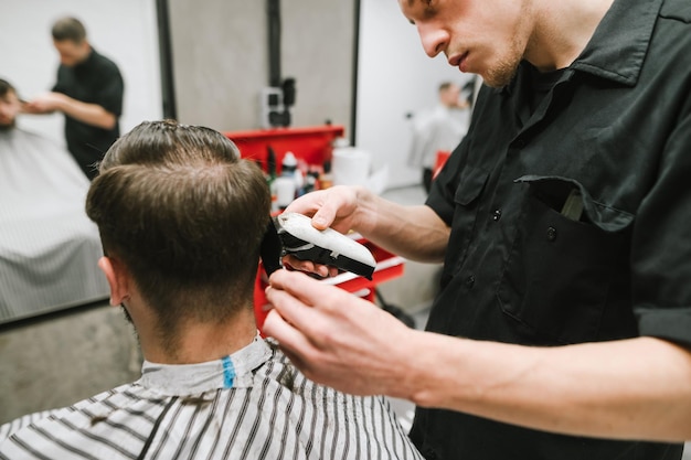 Barbeiro profissional cria um penteado para um cliente em um cabeleireiro masculino aconchegante