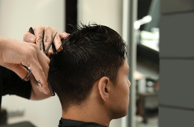 Barbeiro profissional fazendo corte de cabelo estiloso no salão fechado