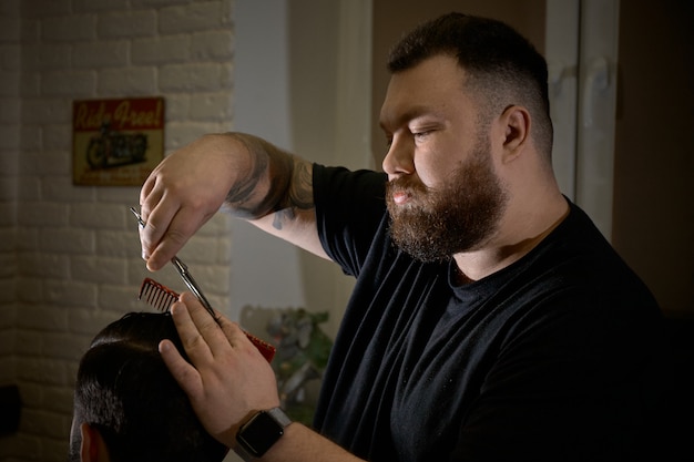 Foto barbeiro profissional fazendo penteado para seu cliente na barbearia