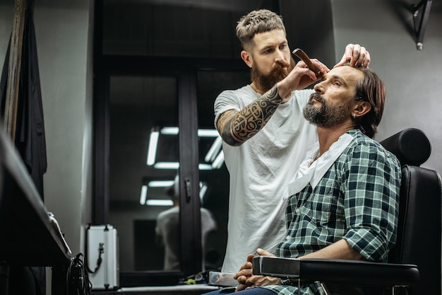 barbeiro segurando navalha enquanto muda o estilo de seu cliente