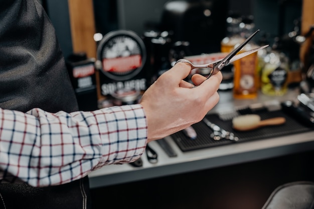 Foto barbeiro segurando uma tesoura na barbearia